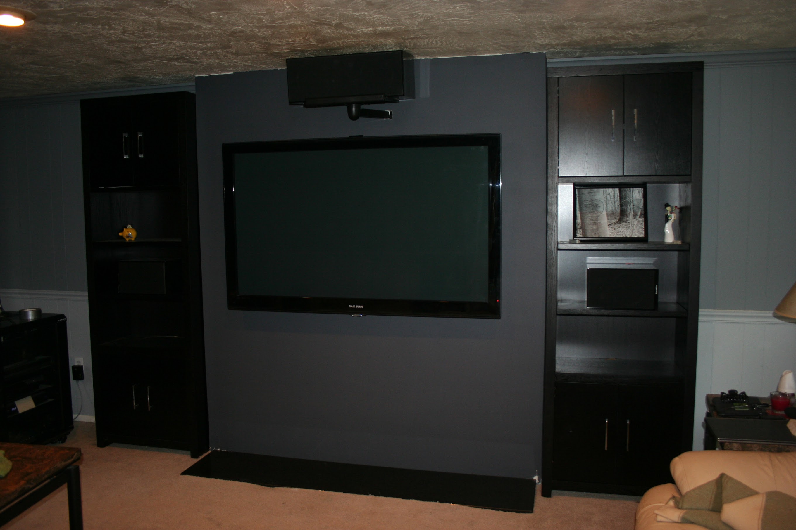 TV mounted with bookshelves flanking, speaker on top